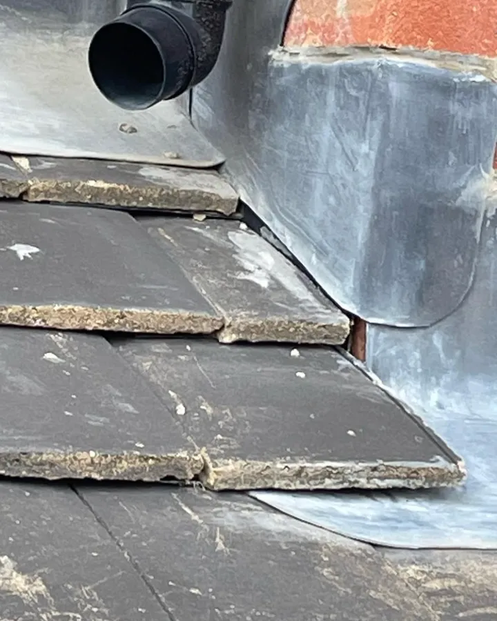 Grey roof slates and lead flashing around a black soil vent pipe.
