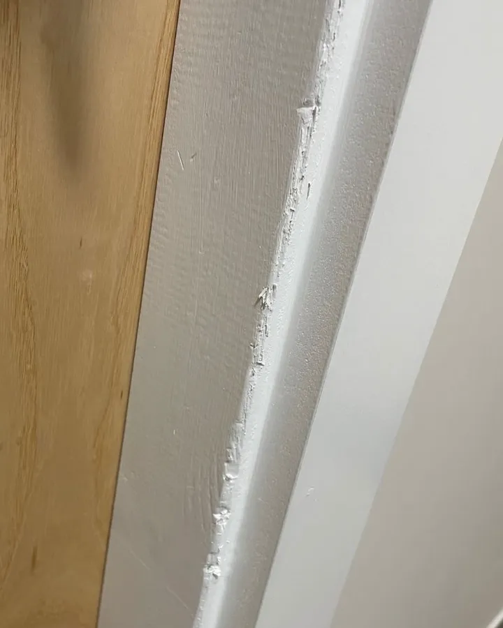 The painted edge of a white door lining beside an oak door.