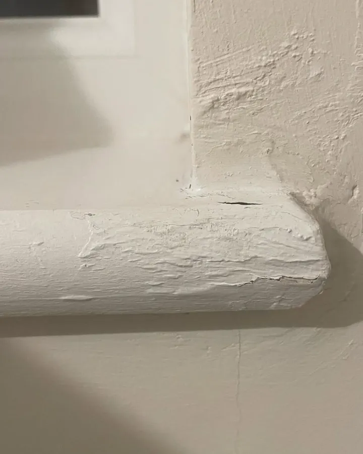 The corner of a painted window board with a rough, lumpy surface.