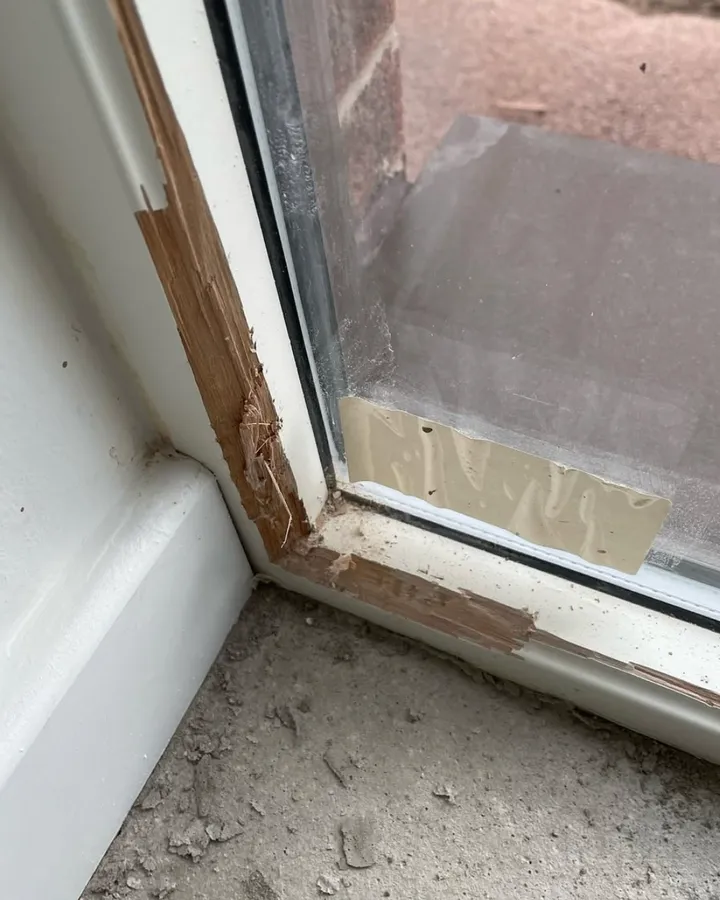 The bottom corner of a glazed door frame, with dust on the sill.